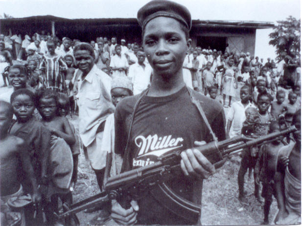 Este niño del ejército de Liberia (África) muestra sonriente su arma